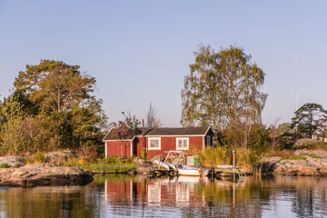 Fototapeta na wymiar Red cottages and fishing boat near Oxelosund in south Sweden