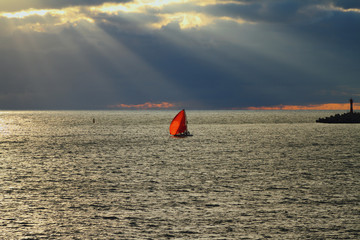 Red sail in sea at sunset