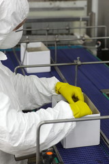 worker in protective uniform mask,gloves working with boxes at on packing line line in factory