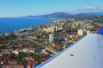 Under plane wing city on sea coast