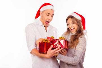 cheerful funny couples with santa hat holding red presents