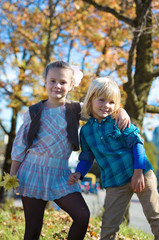 Fototapeta na wymiar Smiling children with autumn leaves in the park