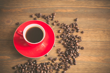 Red coffee cup and coffee beans on  wooden background, pastel toned