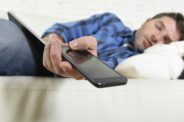 young attractive tired and overworked falling asleep at home couch with mobile phone and digital tablet pad