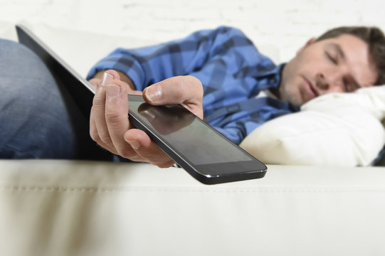 Young Attractive Tired And Overworked Falling Asleep At Home Couch With Mobile Phone And Digital Tablet Pad