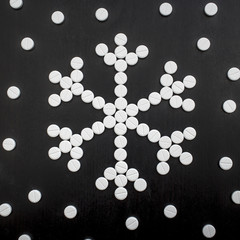concept snowflakes made from medicinal tablets on black background