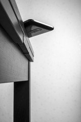 bottom view of the mobile phone is dangerous lies on the edge of the table, carelessly left with the probability of fall