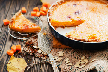American homemade pumpkin pie , pumpkin seeds and autumn leaves on a wooden background