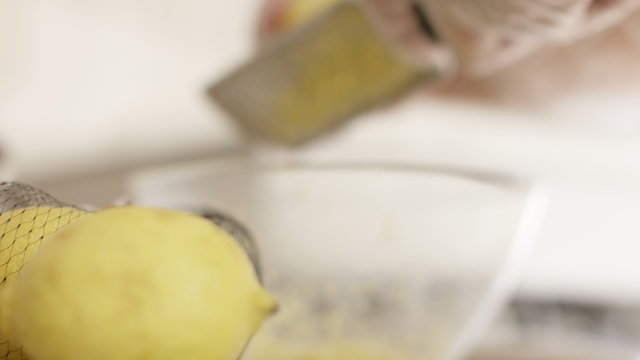 4K Lemon foreground close up as a baker zests a lemon in the background