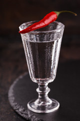 Shot of vodka with chili peppers on a black background.selective focus