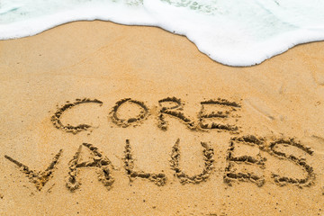 CORE VALUES inscription written on sandy beach with wave approac