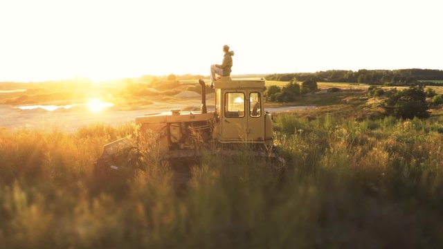 Girl sitting on the dozer in a quarry. Aerial view. Camera around