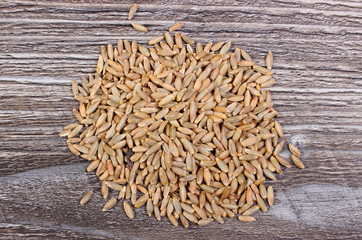 Heap of rye grain on wooden background