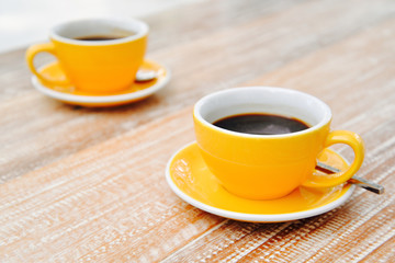Black coffee in orange cup for two on the table.
