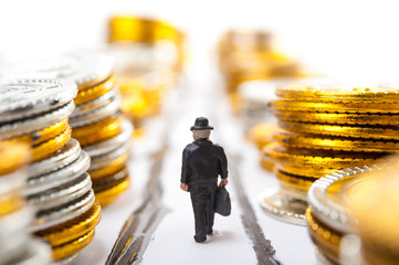 たくさんのお金が積まれている道を歩くビジネスマン