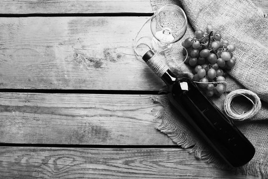 Bottle of wine and grape on wooden table,  black and white retro stylization