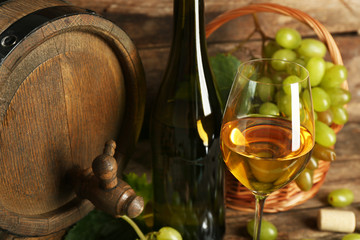 White and red grape with wine bottle near barrel on wooden background