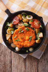 German Weiner schnitzel with vegetables in a pan. Vertical top view
