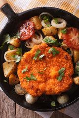 Homemade schnitzel and vegetables on pan close-up. vertical top view
