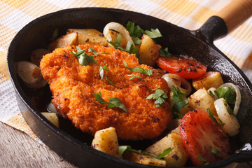 breaded German Weiner schnitzel with fried vegetables in a pan 
