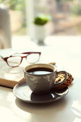 Cup of coffee with biscuits on table in room