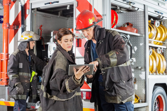Firefighters Using Tablet Computer Against Truck