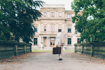 Retro commercial traveler back on his estate walking towards man