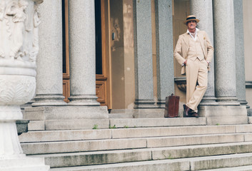 Retro commercial traveler waiting on stairs leaning against colu