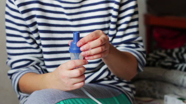 Woman adjusts the inhaler for inhalation.