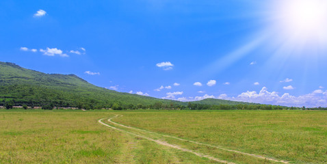 Sunshine on mountain and blue sky with green meadow