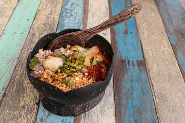 spicy noodles in coconut shell on wood table, asia food