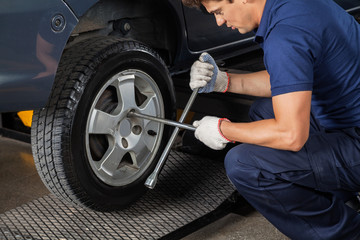 Fototapeta na wymiar Mechanic Using Rim Wrench To Tighten Car Tire