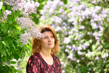 Middle-aged woman near blossoming lilac