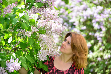 Middle-aged woman near blossoming lilac