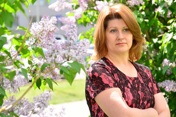 Middle-aged woman near blossoming lilac