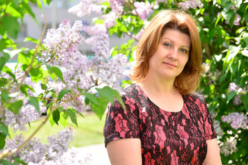 Middle-aged woman near blossoming lilac