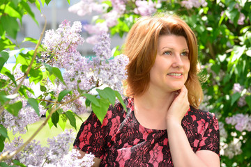 Middle-aged woman near blossoming lilac