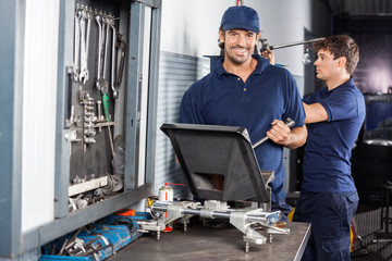Confident Mechanic Holding Wrench At Garage