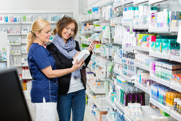 Assistant Showing Product To Customer Holding Cell Phone In Phar