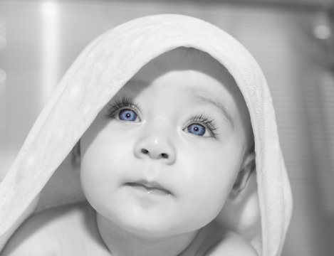 Cheerful baby with blue eyes on towel