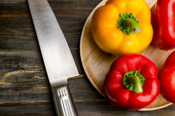 Red and yellow bell pepper or sweet pepper ready for cooking on wooden background