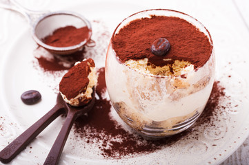 Tiramisu, traditional Italian dessert in a glass,with chocolate spoons.selective focus