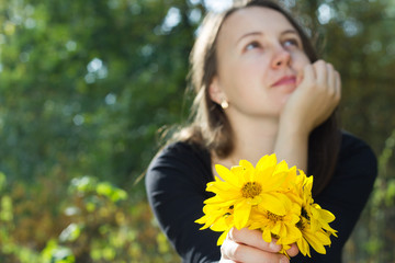 Naklejka premium Beauty girl holding bunch of yellow flowers and enjoying nice se