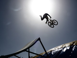 dirtbike bmx rider jumps against sun