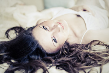 Naklejka premium brown-haired woman lying on her duvet in her bedroom