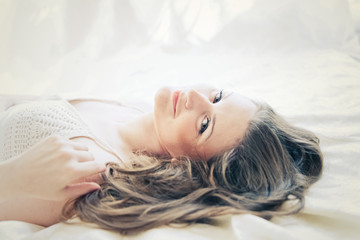 Fototapeta premium brown-haired woman lying on her duvet in her bedroom