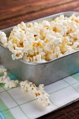 Aluminum plate full of salty popcorn on towel