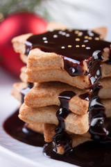 Christmas cookies with chocolate syrup and sugar balls on a white plate.