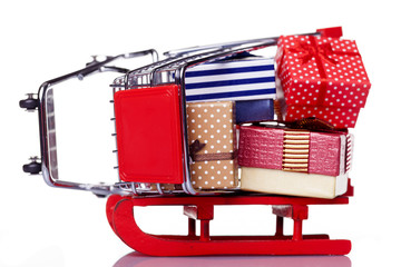 Red sled and shopping cart with gift boxes, isolated on white ba