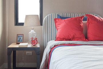 Red and blue pillows on the cozy bed with striped headboard